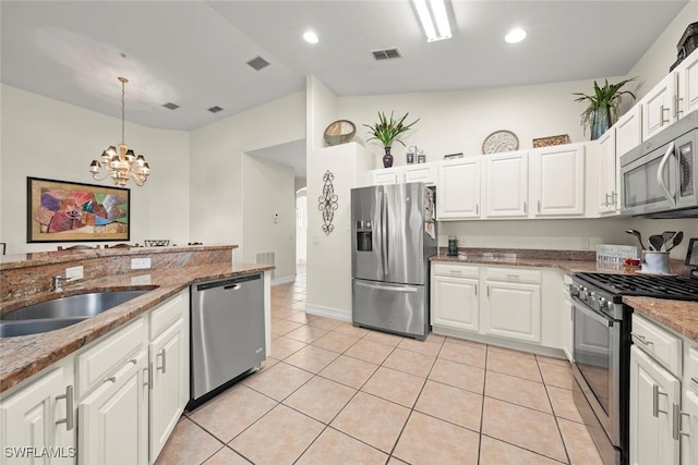 kitchen with white cabinetry, decorative light fixtures, light tile patterned floors, dark stone counters, and stainless steel appliances