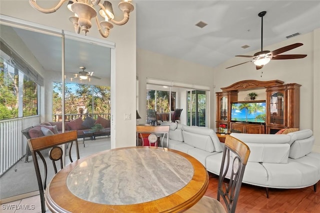 dining space featuring lofted ceiling, ceiling fan with notable chandelier, and hardwood / wood-style floors