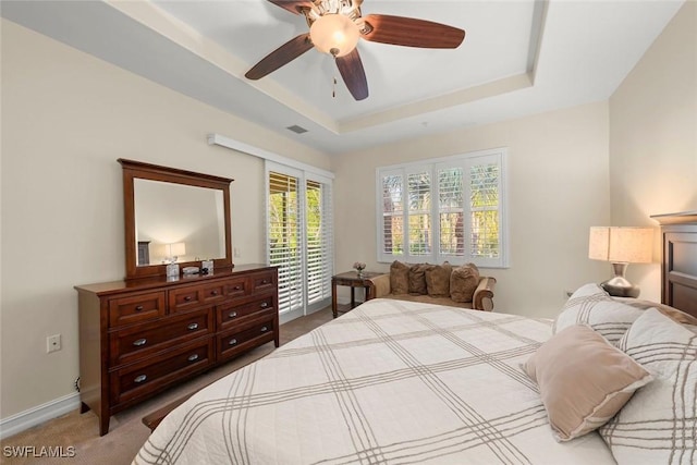 carpeted bedroom with ceiling fan, access to exterior, and a raised ceiling