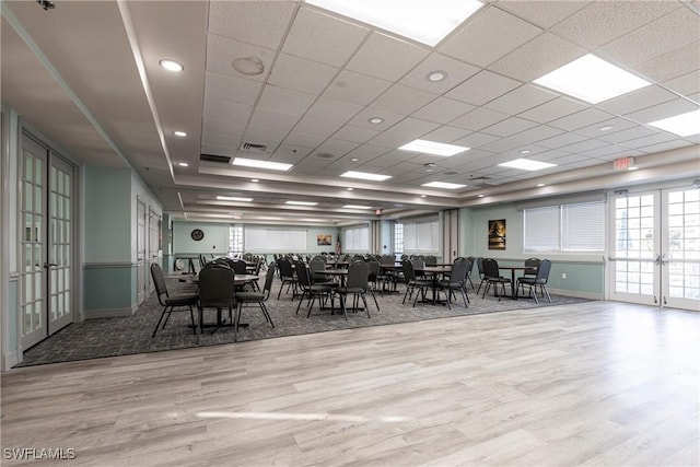 unfurnished dining area with french doors, a paneled ceiling, and light wood-type flooring