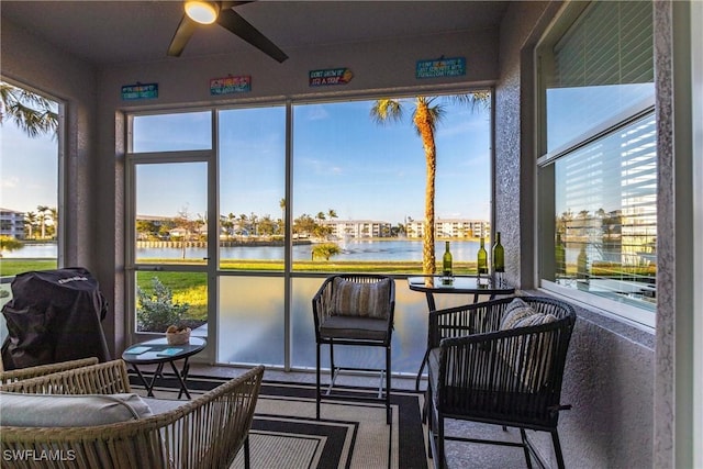 sunroom / solarium featuring a water view and ceiling fan