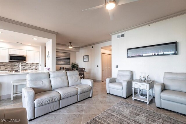 living room with ornamental molding, light tile patterned floors, and ceiling fan