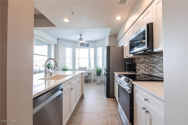 kitchen with appliances with stainless steel finishes, tasteful backsplash, sink, white cabinets, and crown molding