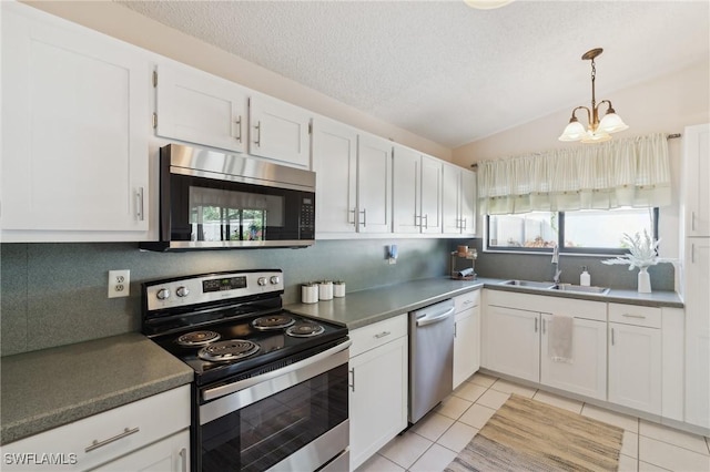 kitchen with lofted ceiling, sink, appliances with stainless steel finishes, white cabinets, and backsplash