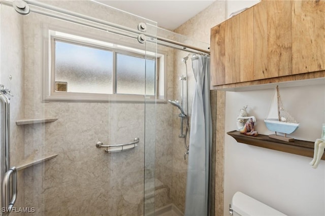 bathroom featuring a shower with door and toilet