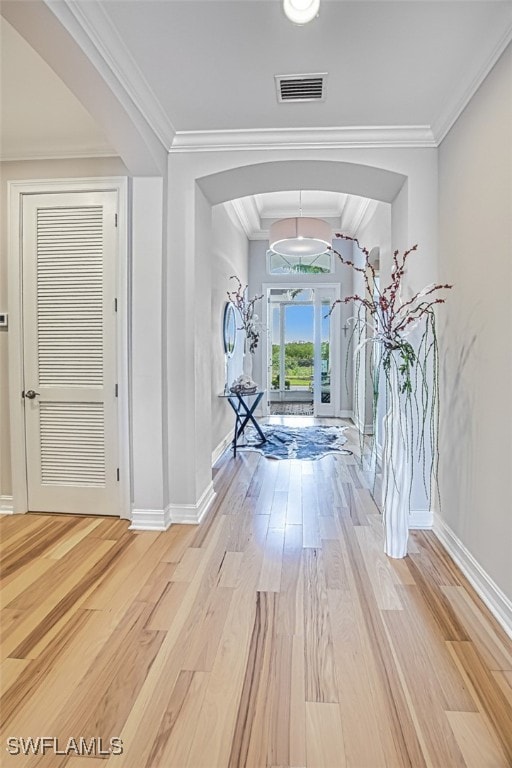 hall with baseboards, visible vents, wood finished floors, and ornamental molding