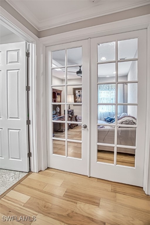 doorway to outside featuring ornamental molding, french doors, and light wood finished floors