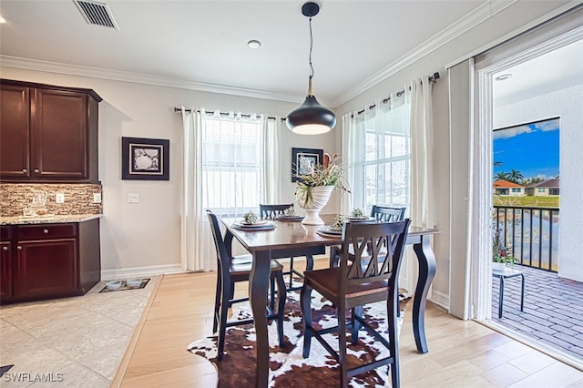 dining space with a healthy amount of sunlight, visible vents, and ornamental molding