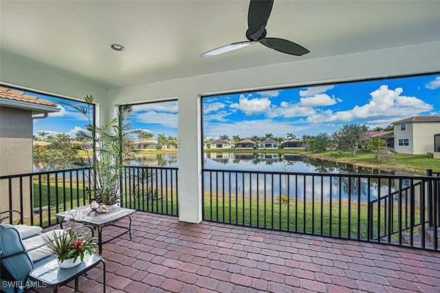 sunroom / solarium with a water view and a ceiling fan