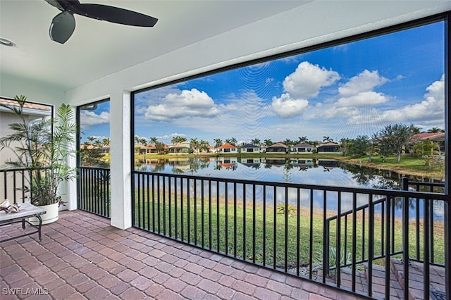 unfurnished sunroom featuring a ceiling fan and a water view