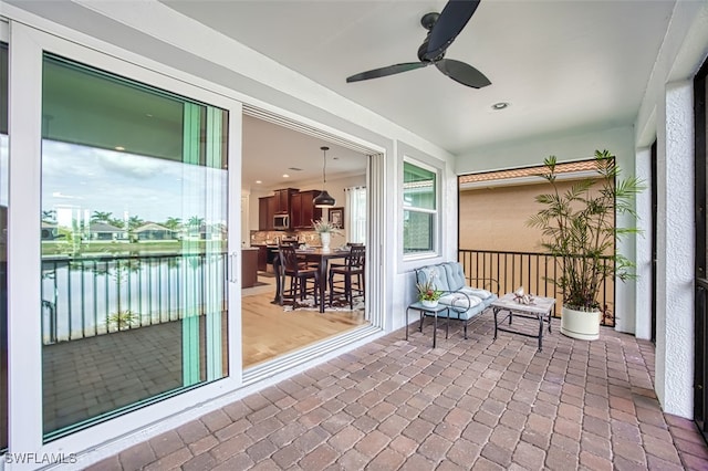 sunroom featuring ceiling fan and a water view