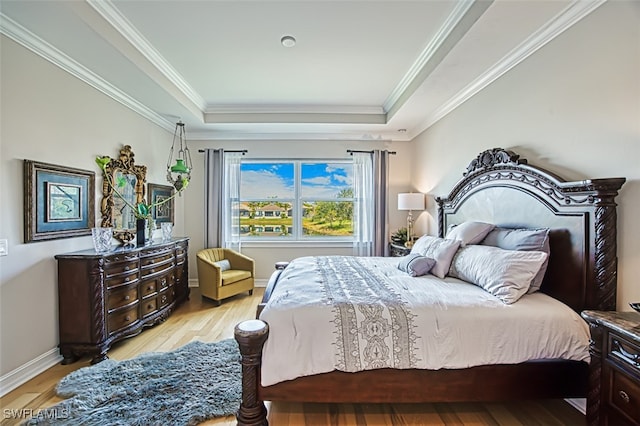 bedroom featuring light wood-type flooring, a raised ceiling, crown molding, and baseboards