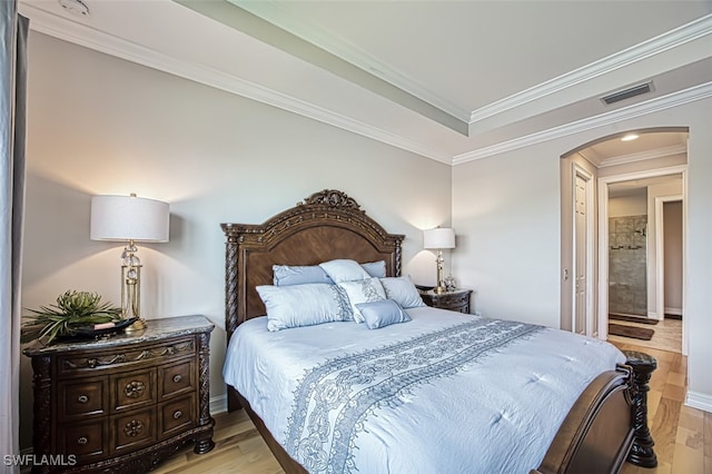 bedroom featuring arched walkways, visible vents, baseboards, ornamental molding, and light wood-type flooring