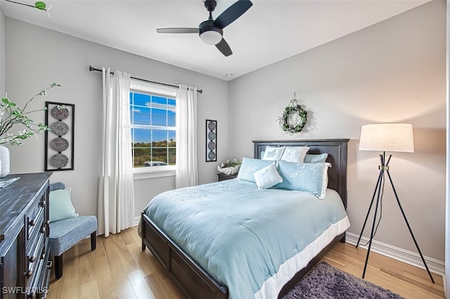 bedroom featuring baseboards, light wood-style flooring, and a ceiling fan