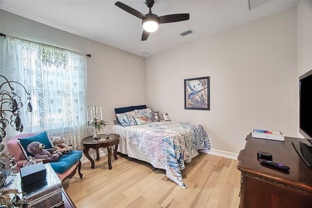 bedroom with light wood finished floors, baseboards, visible vents, and ceiling fan