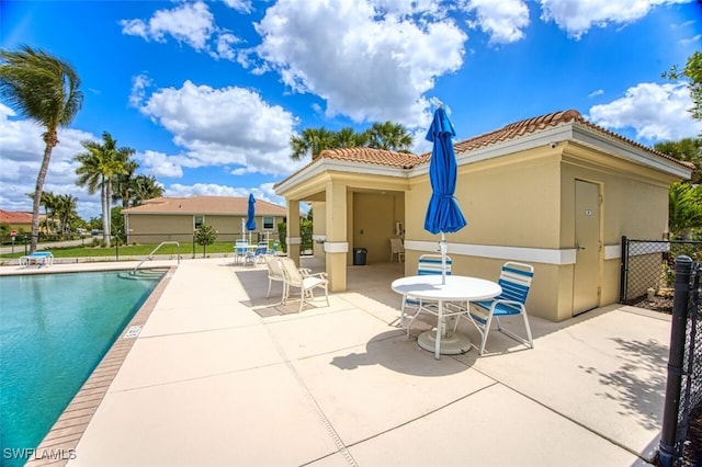 exterior space featuring a tile roof, a patio, stucco siding, fence, and a community pool