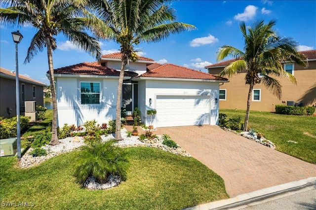 view of front of home featuring decorative driveway, stucco siding, a front yard, a garage, and a tiled roof