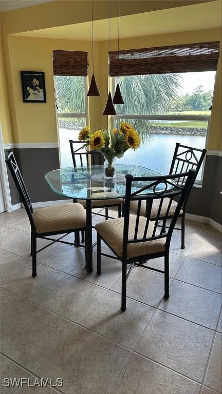 dining room featuring a healthy amount of sunlight, a water view, and light tile patterned flooring