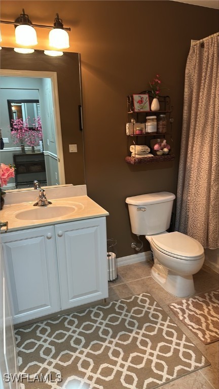 full bathroom featuring a shower with shower curtain, toilet, vanity, tile patterned flooring, and baseboards