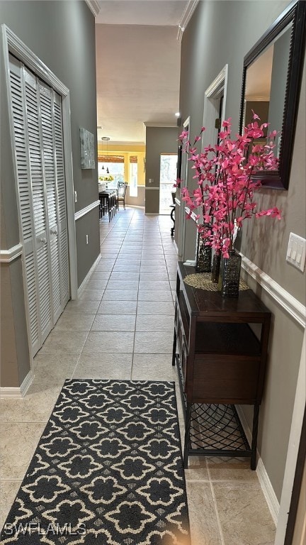 hall featuring tile patterned floors, baseboards, and ornamental molding