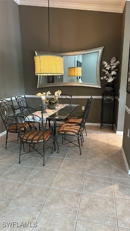 tiled dining room featuring crown molding and baseboards