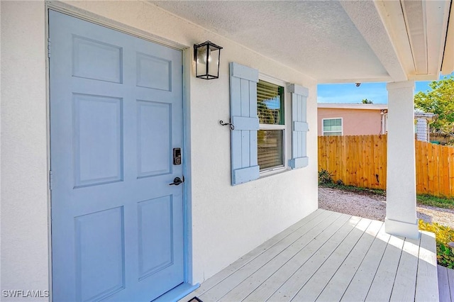 entrance to property with fence and stucco siding