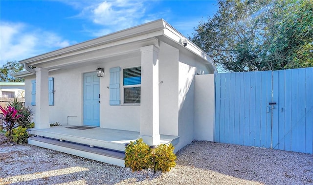 exterior space with covered porch, fence, and stucco siding