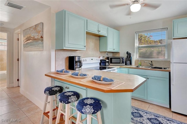 kitchen with a breakfast bar, a wealth of natural light, a sink, blue cabinets, and white appliances