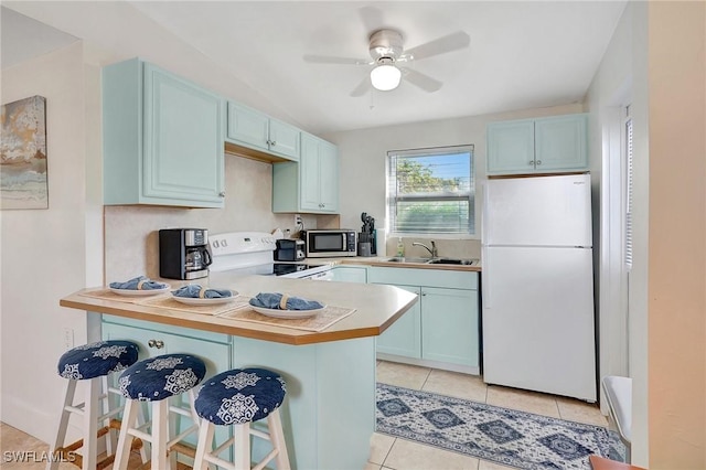 kitchen featuring white appliances, light tile patterned floors, a breakfast bar, a peninsula, and a sink