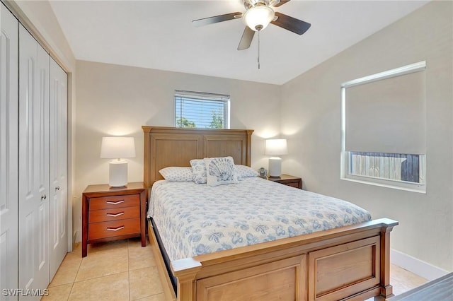 bedroom featuring a closet, light tile patterned flooring, ceiling fan, and baseboards