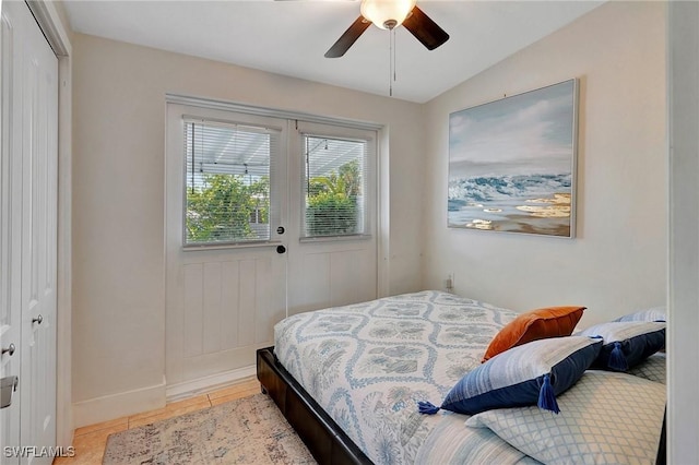 bedroom with a closet, a ceiling fan, light tile patterned flooring, vaulted ceiling, and baseboards