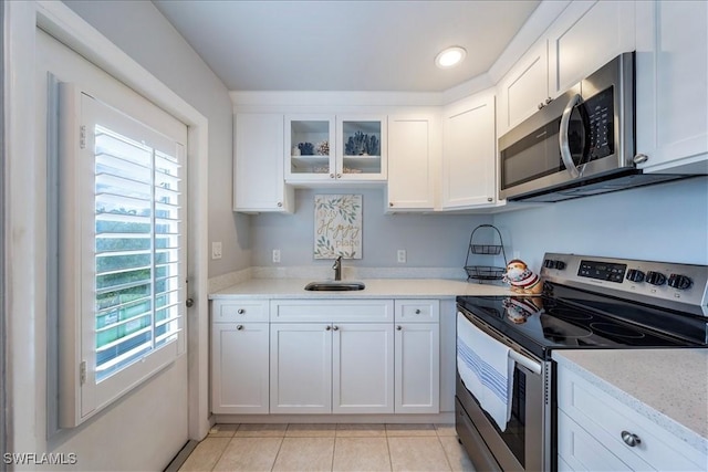 kitchen featuring light stone countertops, light tile patterned flooring, white cabinets, and appliances with stainless steel finishes