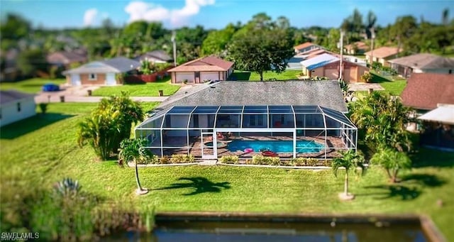 back of house featuring a water view, glass enclosure, and a lawn