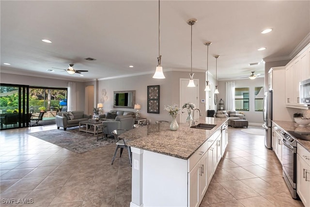 kitchen with white cabinetry, sink, a kitchen island with sink, light stone counters, and stainless steel appliances