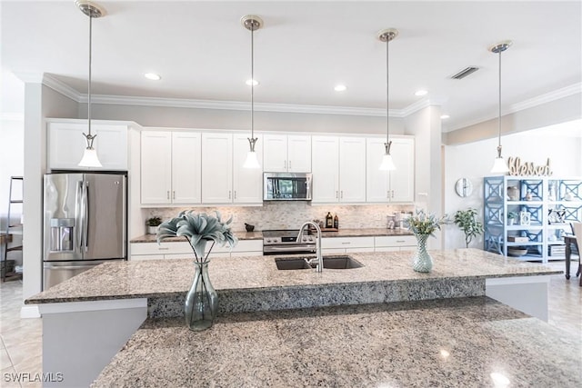 kitchen with pendant lighting, white cabinets, a kitchen island with sink, light stone counters, and stainless steel appliances