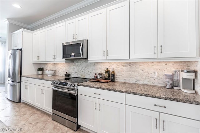 kitchen featuring appliances with stainless steel finishes, tasteful backsplash, white cabinetry, dark stone countertops, and crown molding