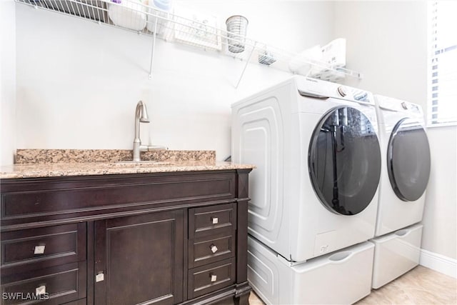 laundry area featuring cabinets, separate washer and dryer, and sink