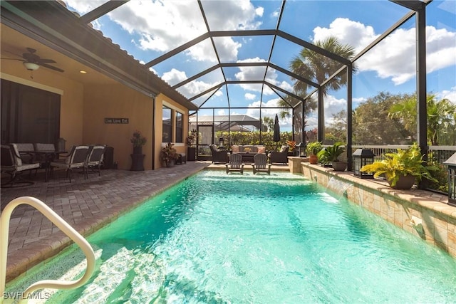 view of pool with pool water feature, a lanai, ceiling fan, an outdoor living space, and a patio