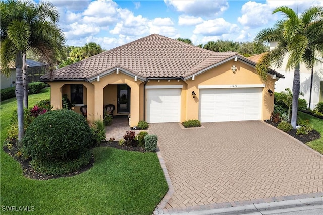 mediterranean / spanish-style house featuring a garage and a front lawn