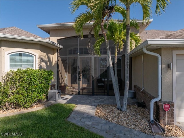 view of exterior entry featuring a shingled roof, french doors, and stucco siding