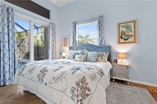 bedroom with baseboards, wood finished floors, and access to outside