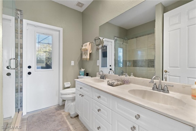 bathroom featuring a shower stall, toilet, visible vents, and a sink