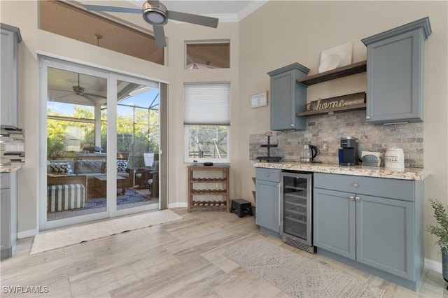 kitchen with gray cabinets, open shelves, light stone counters, backsplash, and wine cooler