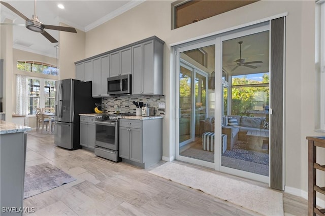 kitchen with decorative backsplash, gray cabinets, stainless steel appliances, and ornamental molding