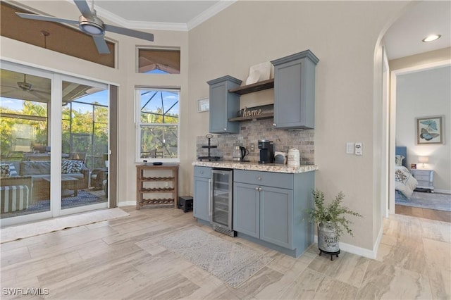 bar featuring a ceiling fan, baseboards, ornamental molding, wine cooler, and tasteful backsplash