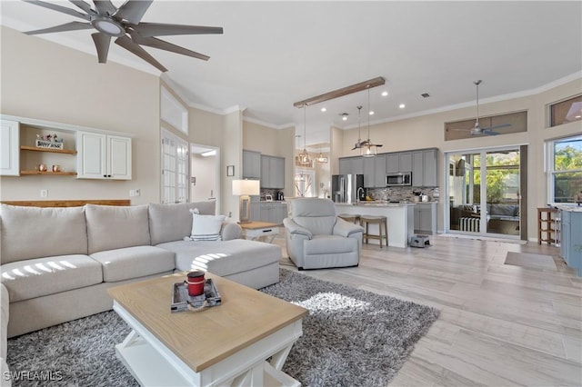 living area with crown molding, a towering ceiling, and ceiling fan