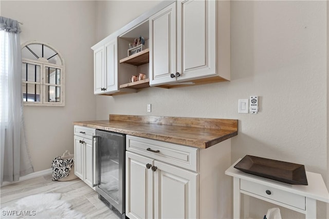 kitchen featuring white cabinetry, open shelves, beverage cooler, and wooden counters