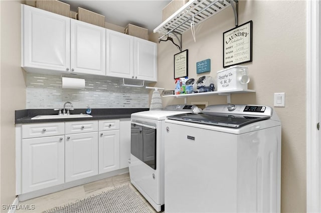 clothes washing area with washer and dryer, cabinet space, and a sink