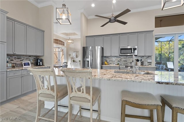 kitchen with gray cabinetry, stainless steel appliances, and ornamental molding