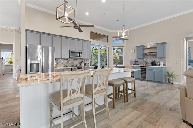 kitchen featuring gray cabinetry, beverage cooler, arched walkways, and stainless steel appliances